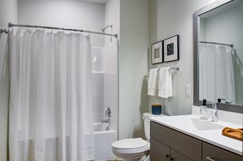 A white bathroom with a toilet, sink, and shower curtain.